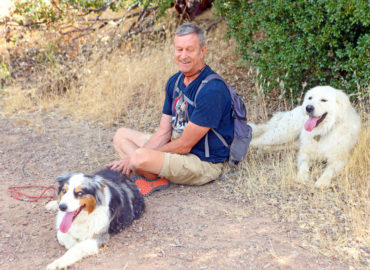 Milt is sitting with his dog Orion (left) and Molly (right)